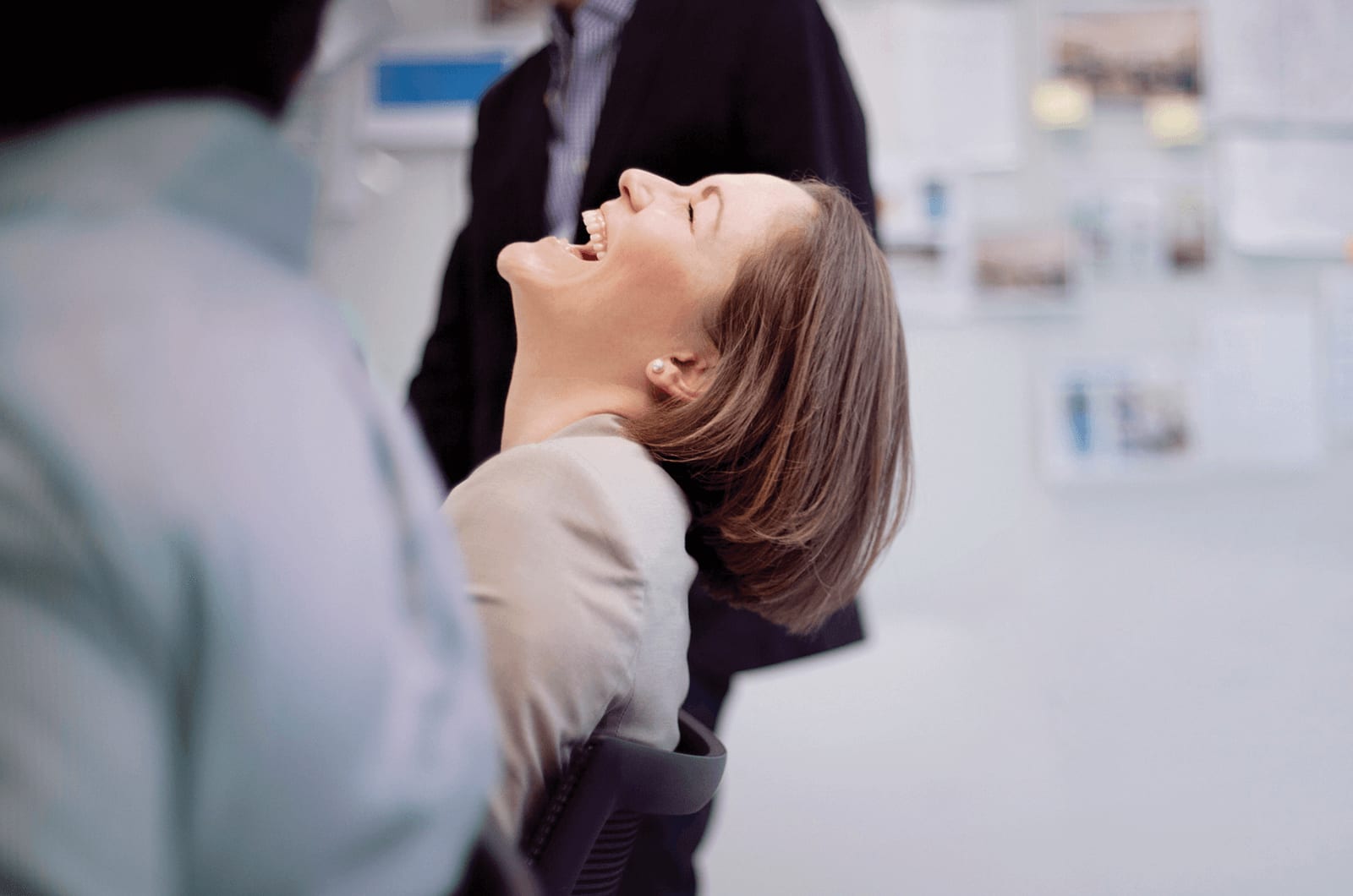 A seated woman with her head thrown back in laughter