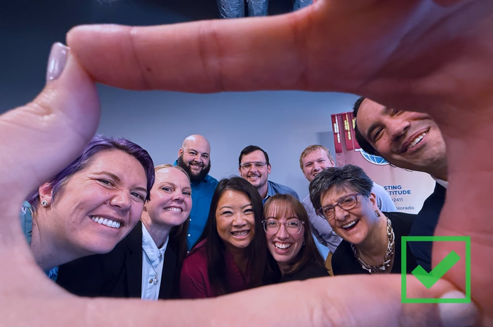 People smiling and framed by two connecting index fingers and thumbs