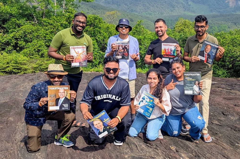 Eight people holding magazines while hiking a mountain