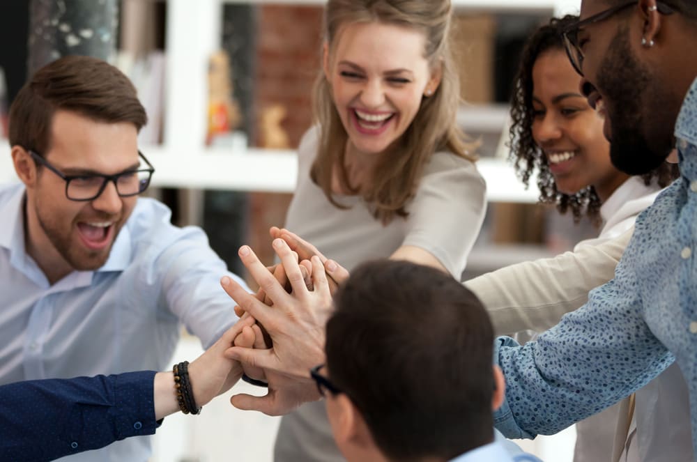 Group of people standing in a circle with their hands in the middle
