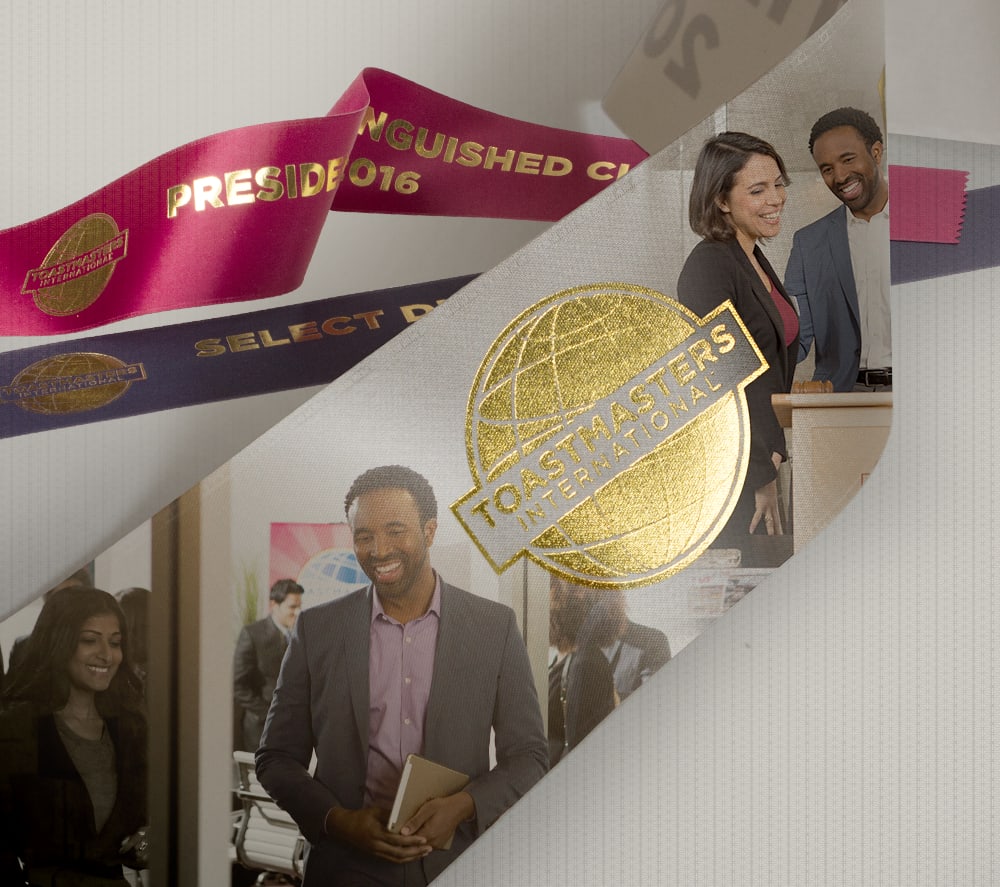 Three ribbons overlapping with the front ribbon showing the Toastmasters International logo next to an image of a man and woman standing at a lectern.