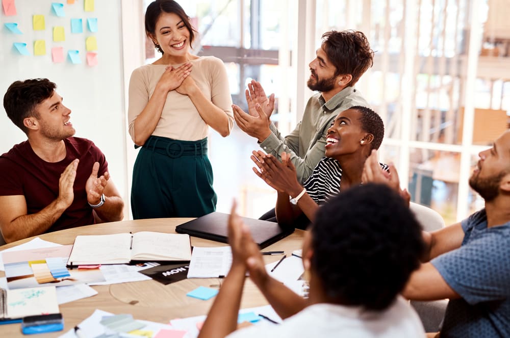 A group of diverse individuals enthusiastically collaborating in a creative workspace, surrounded by colorful notes and office supplies.