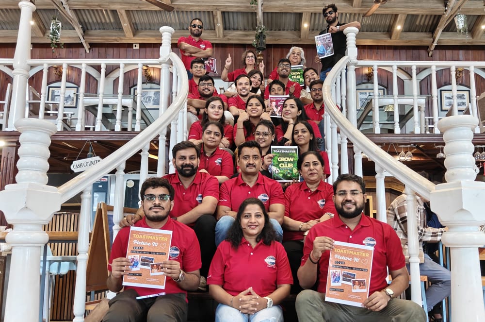 A group of people wearing red shirts, posing together on a wooden staircase in what appears to be a rural or rustic setting.