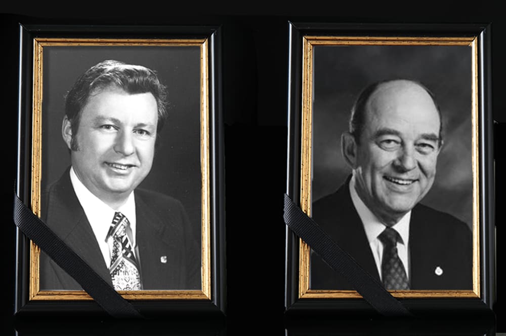 Two framed black and white portraits of men in formal attire against a dark background.