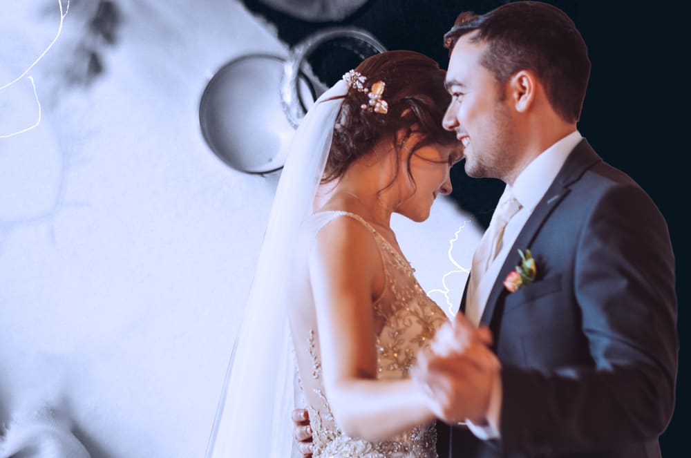 Two wedding rings sitting near a bow in front a white-and-black background