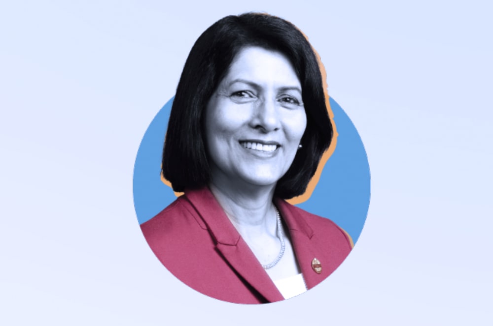 A smiling woman wearing a red suit jacket with a blue circle in the background