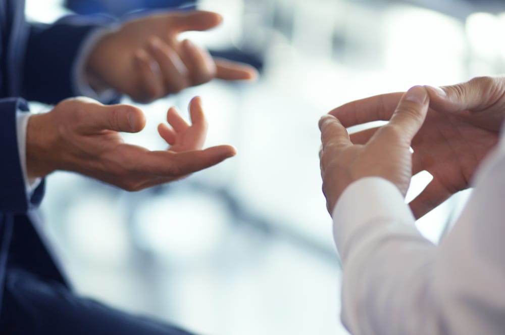 Hands reaching out and interacting in a blurred, out-of-focus background.