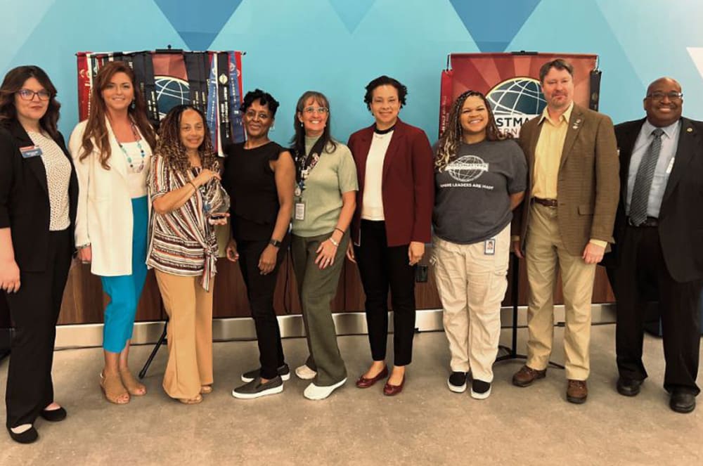 A group of people, both men and women, are standing together in front of a backdrop with geometric patterns and the STEM logo.
