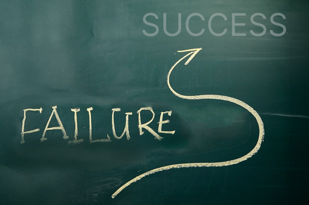 The image depicts a chalkboard with the words "SUCCESS" and "FAILURE" written on it, with an arrow pointing from "FAILURE" to "SUCCESS", suggesting that failure can lead to success.