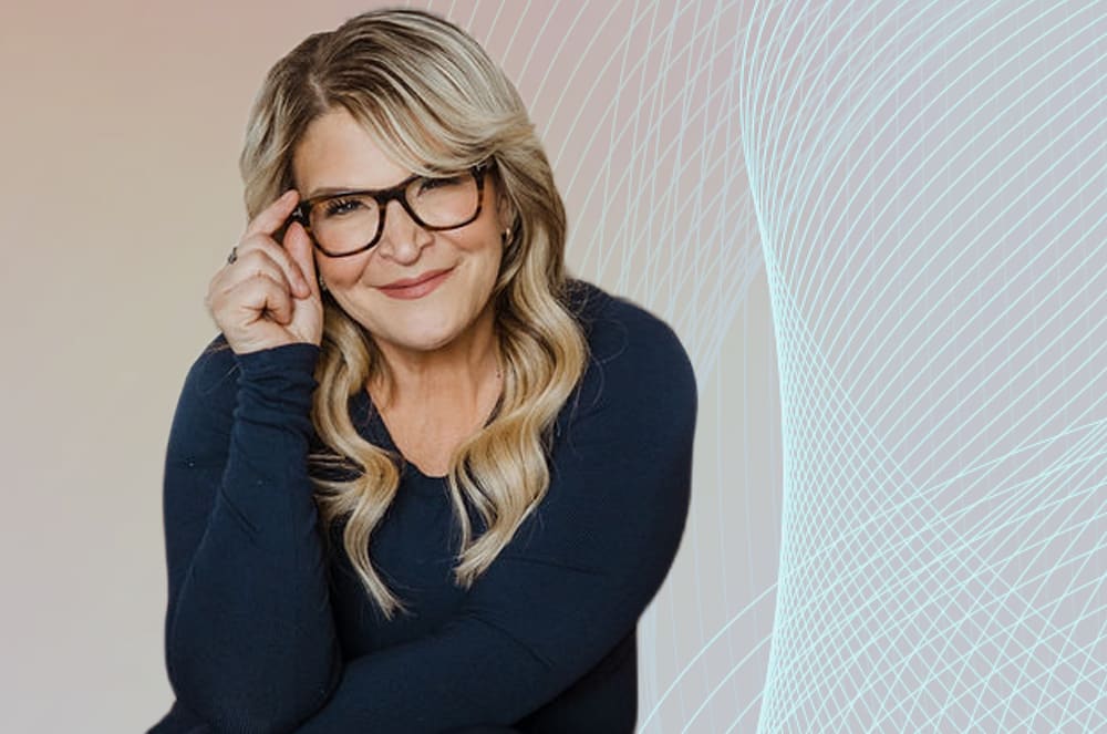 A woman with blonde hair and glasses smiles while adjusting her eyewear, with a soft gradient background and a light blue wave pattern on the right.