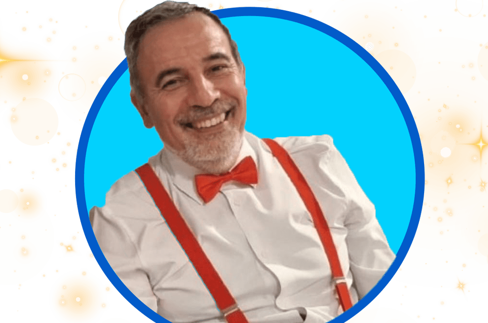A smiling man with a red bowtie and suspenders is framed by a blue circle against a bright, star-speckled background.