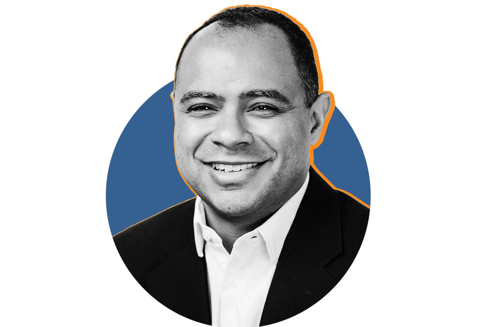 A smiling man in a suit is in the foreground against a blue circle with an orange outline in the background.