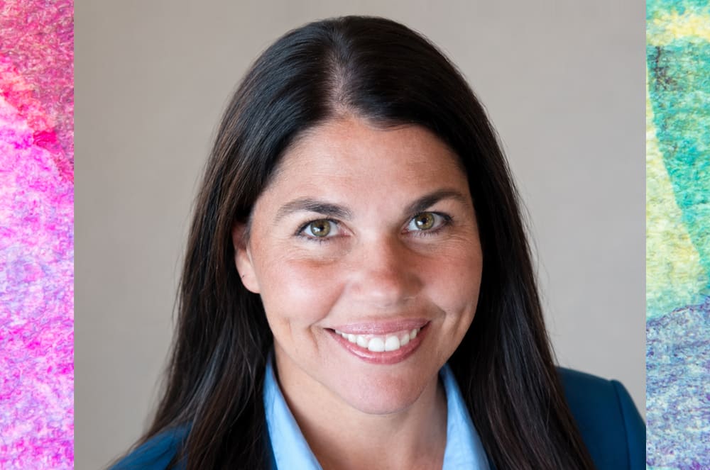 A smiling woman wearing a blue suit jacket
