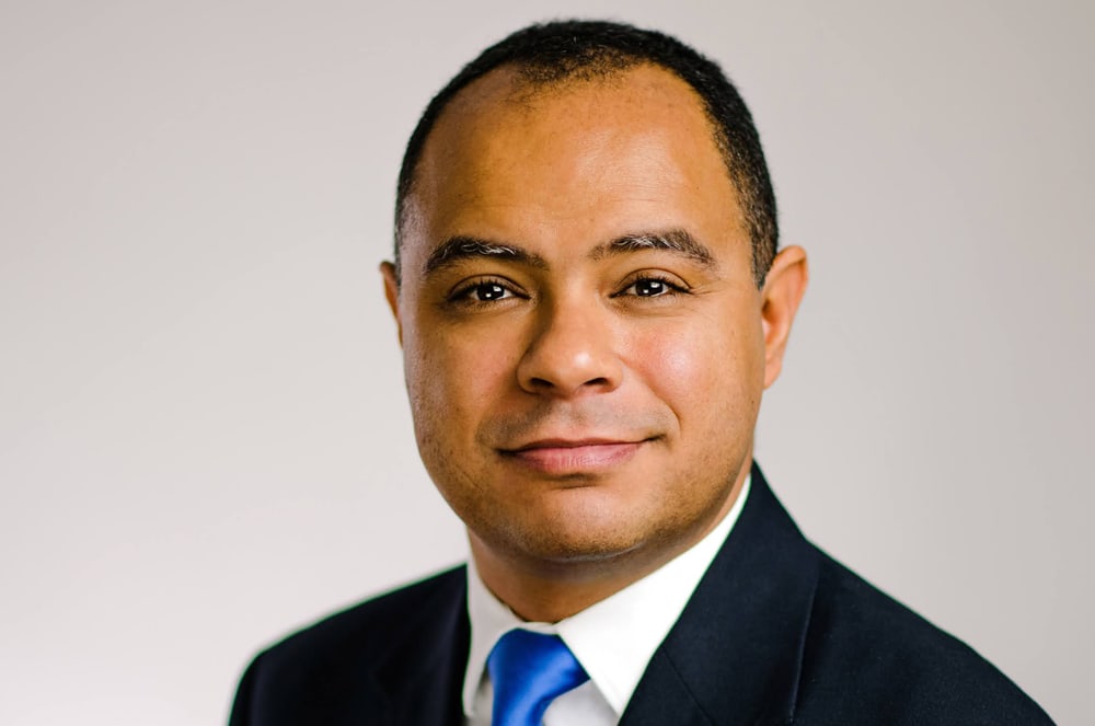 A smiling man wearing a suit and tie