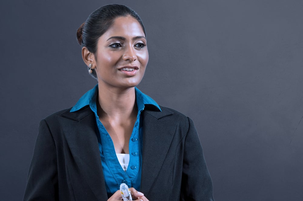 A smiling woman wearing a black blazer holding her hands together