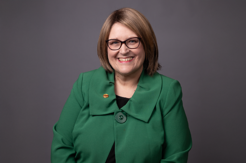 Woman in green shirt and glasses smiling