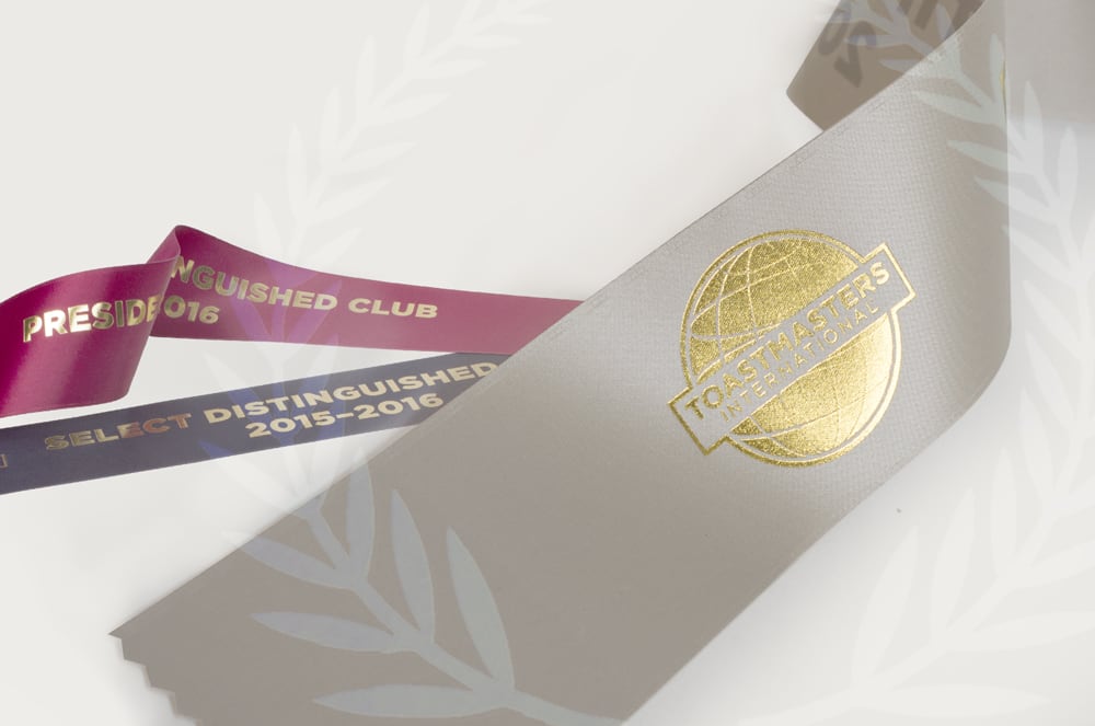 Three ribbons overlapping with the front ribbon showing the Toastmasters International logo