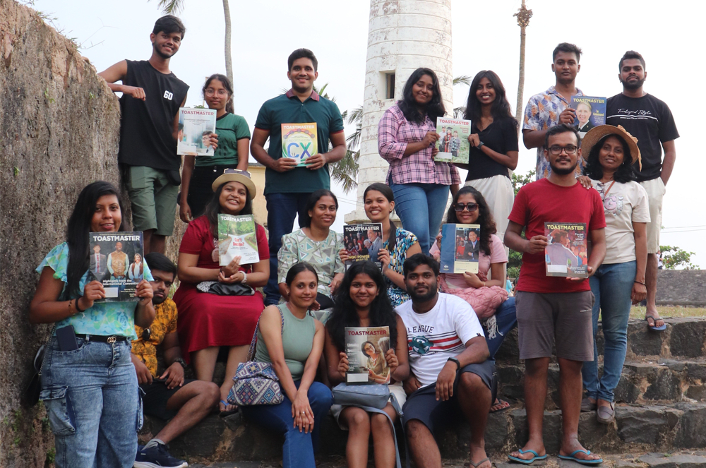 A group of people holding magazines outside in front of a fort